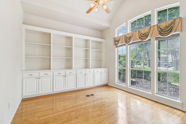 spare room featuring a ceiling fan, a high ceiling, baseboards, and light wood-type flooring