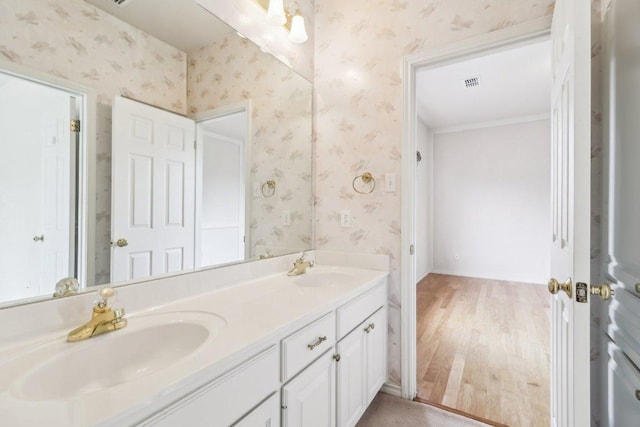 full bath featuring a sink, wood finished floors, and wallpapered walls