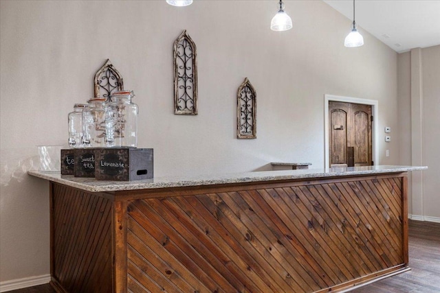 bar featuring pendant lighting, baseboards, a bar, and wood finished floors