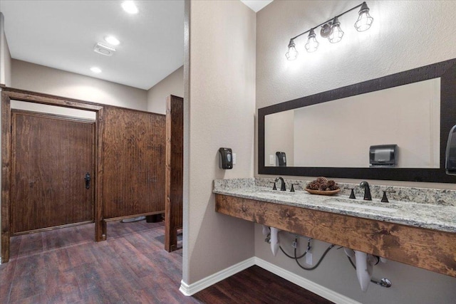 bathroom featuring baseboards, a sink, and wood finished floors