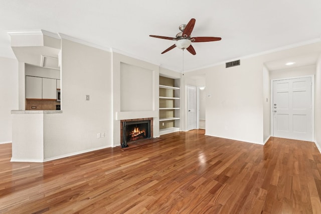 unfurnished living room with visible vents, ceiling fan, wood finished floors, and built in shelves