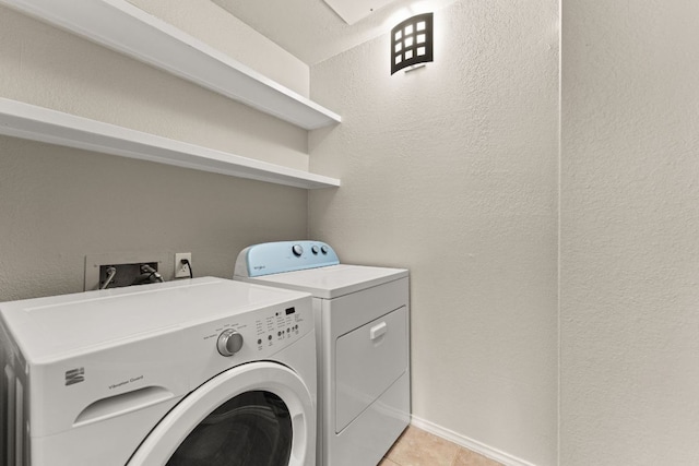 laundry room featuring a textured wall, laundry area, light tile patterned flooring, and washer and clothes dryer