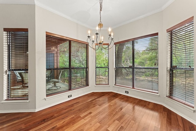 unfurnished dining area with baseboards, a chandelier, ornamental molding, and wood finished floors