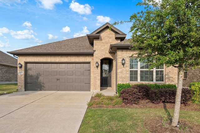 view of front of property featuring brick siding, an attached garage, driveway, and roof with shingles