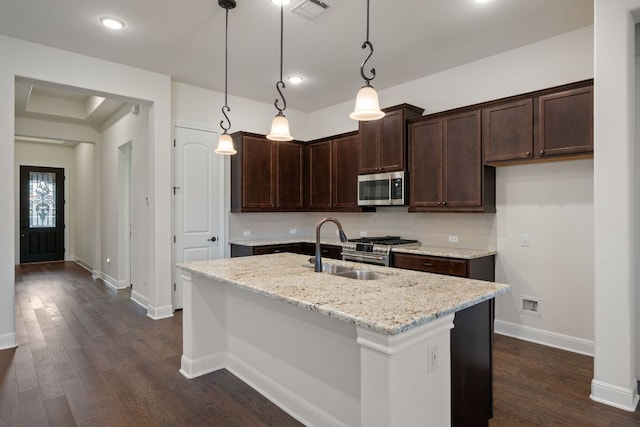 kitchen with dark brown cabinetry, light stone countertops, a sink, stainless steel appliances, and visible vents
