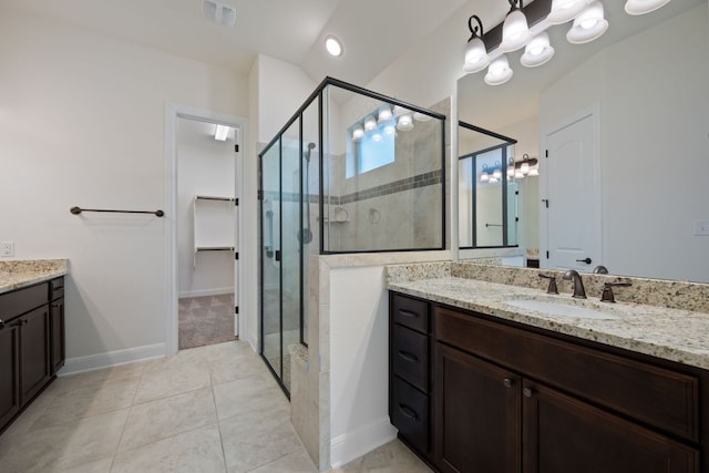 bathroom with a walk in closet, vanity, tile patterned floors, baseboards, and a shower stall