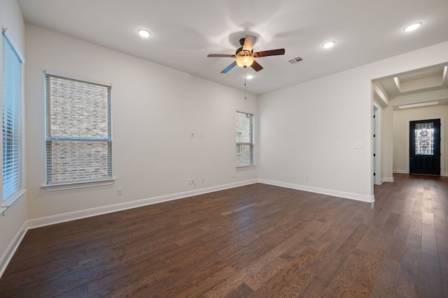 empty room with visible vents, dark wood-style flooring, ceiling fan, and baseboards