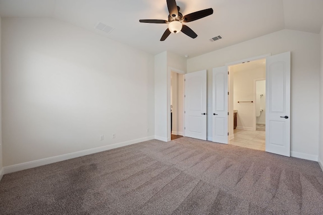unfurnished bedroom featuring visible vents, light carpet, ensuite bathroom, and lofted ceiling