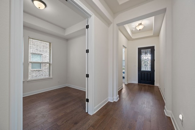 foyer entrance with baseboards, dark wood-style floors, and a raised ceiling