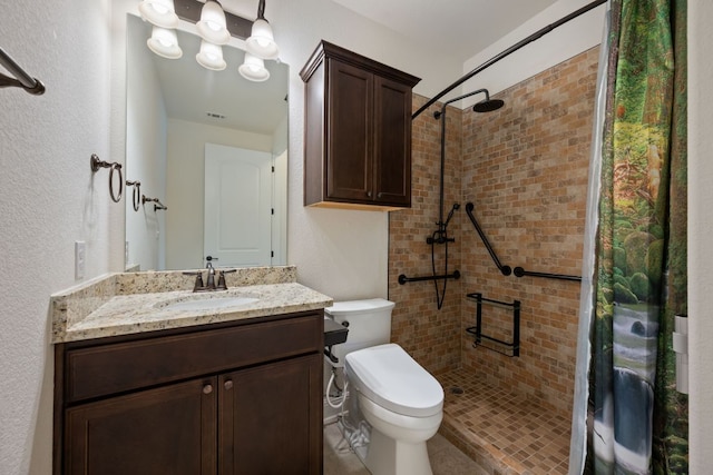 full bathroom with toilet, a tile shower, and vanity