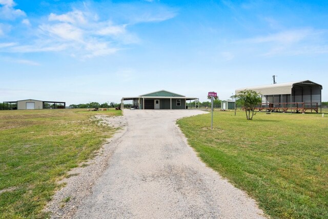view of front of home with a garage, a front lawn, a detached carport, and gravel driveway