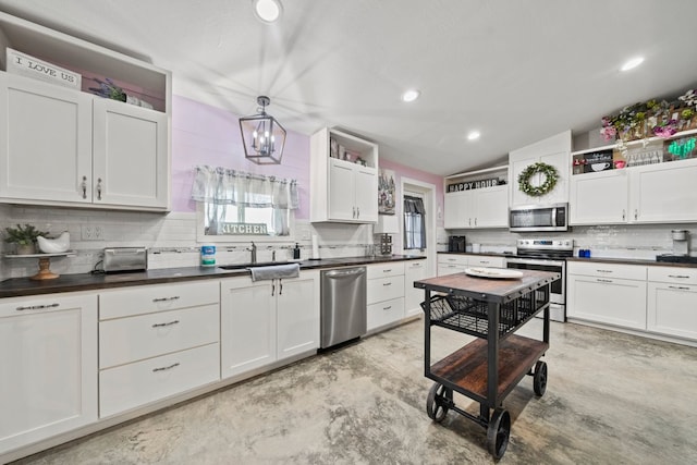 kitchen featuring white cabinets, dark countertops, appliances with stainless steel finishes, a sink, and backsplash