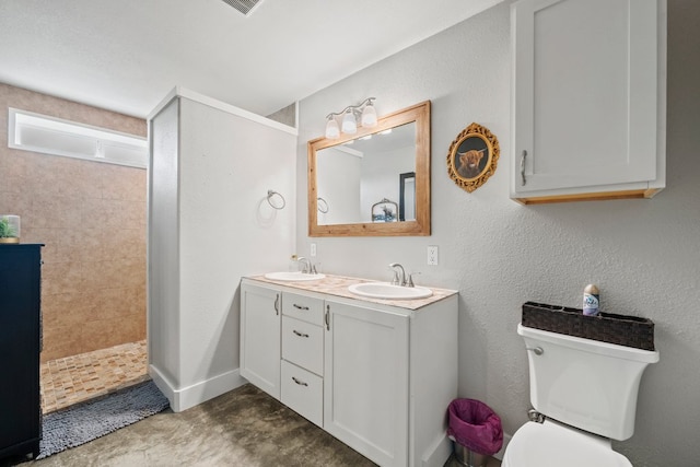 full bathroom with double vanity, a sink, a walk in shower, and toilet