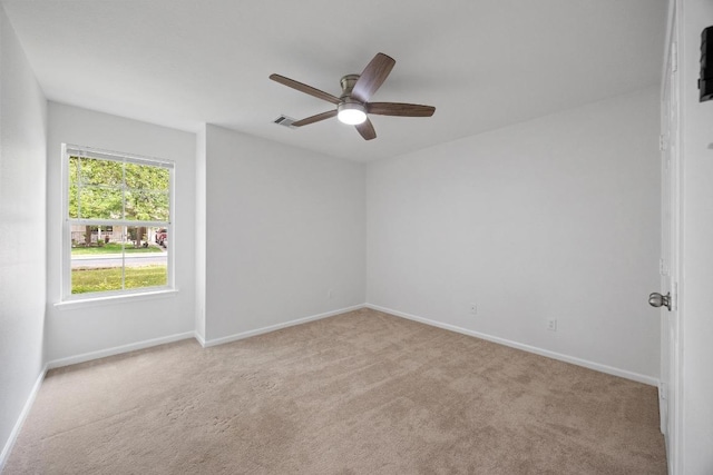 carpeted spare room with visible vents, baseboards, and ceiling fan
