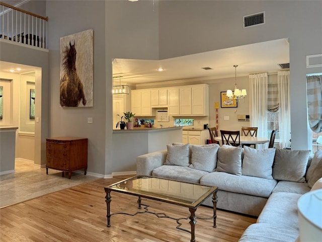 12600 Schreiner Ct, Austin, TX 78732 - living room featuring a towering ceiling, a chandelier, baseboards, and light wood-type flooring