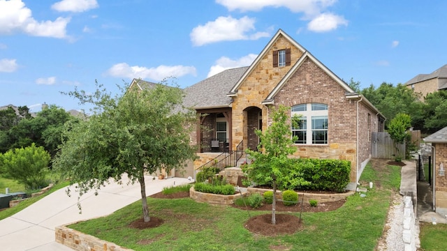 view of front of home featuring fence, stone siding, a front yard, and brick siding