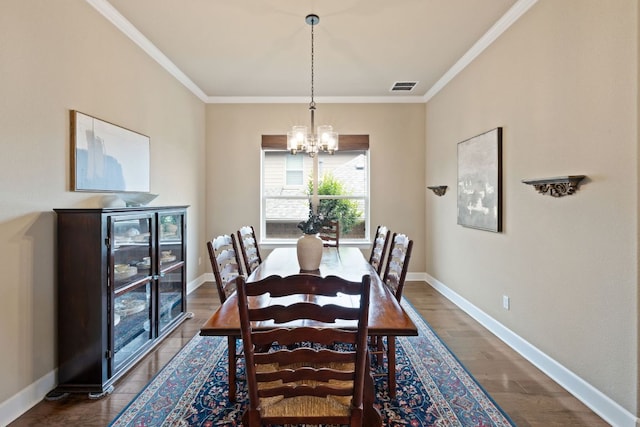 dining room with an inviting chandelier, ornamental molding, visible vents, and dark wood-type flooring