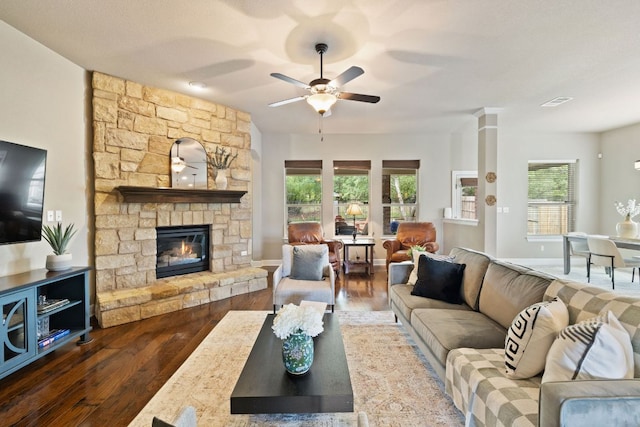 living room with a ceiling fan, a stone fireplace, and wood finished floors