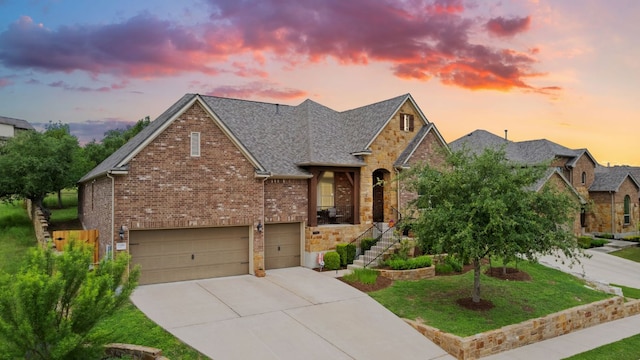 view of front facade featuring roof with shingles, a yard, a garage, brick siding, and concrete driveway