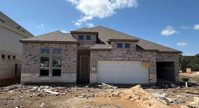 french country home with roof with shingles, dirt driveway, and brick siding