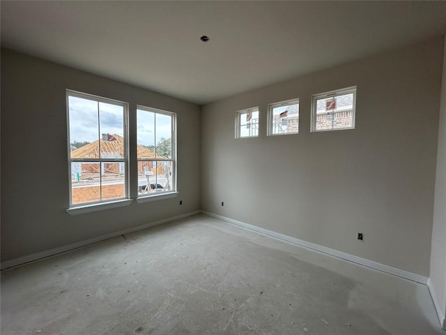unfurnished room with baseboards and concrete flooring