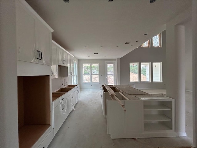 kitchen with baseboards, concrete flooring, and white cabinetry