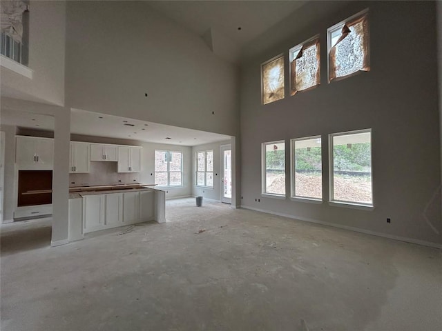 unfurnished living room with a high ceiling and baseboards