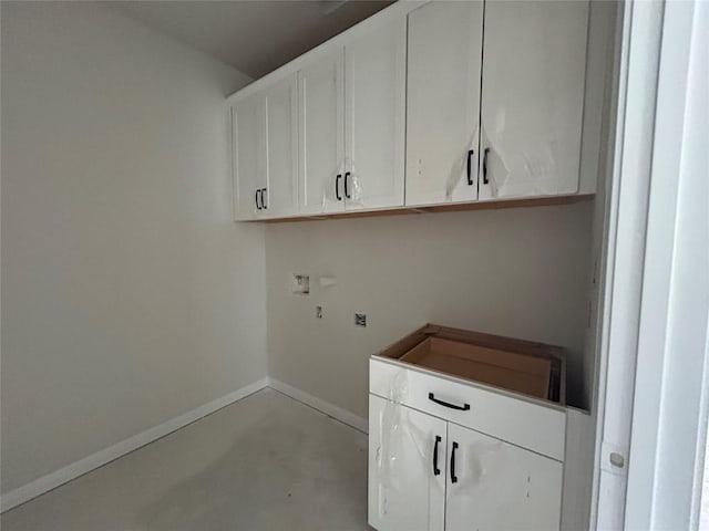 washroom with baseboards, washer hookup, and cabinet space