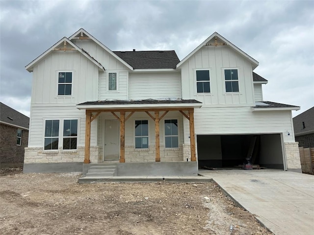 view of front of home with concrete driveway, board and batten siding, an attached garage, and stone siding