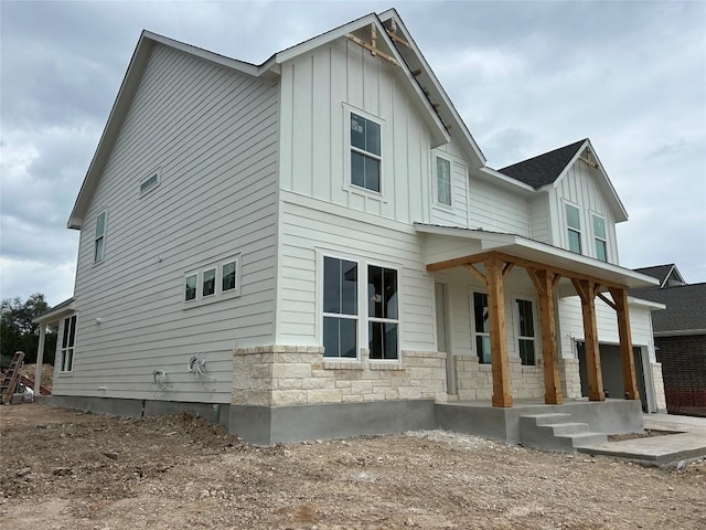 view of side of home with a porch, board and batten siding, and stone siding