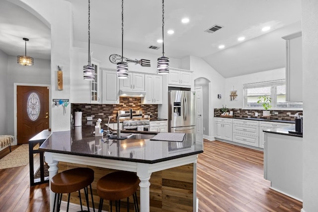 kitchen with under cabinet range hood, arched walkways, visible vents, and stainless steel appliances