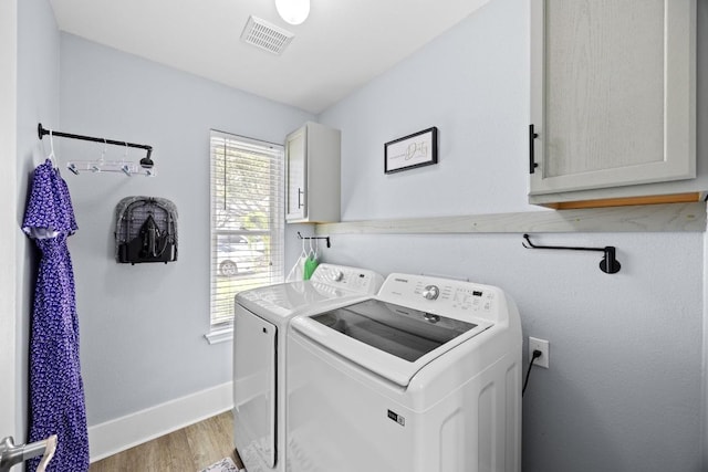 laundry area featuring visible vents, baseboards, light wood-style floors, cabinet space, and independent washer and dryer