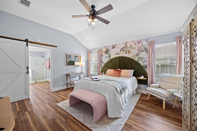bedroom with visible vents, a barn door, wood finished floors, and vaulted ceiling