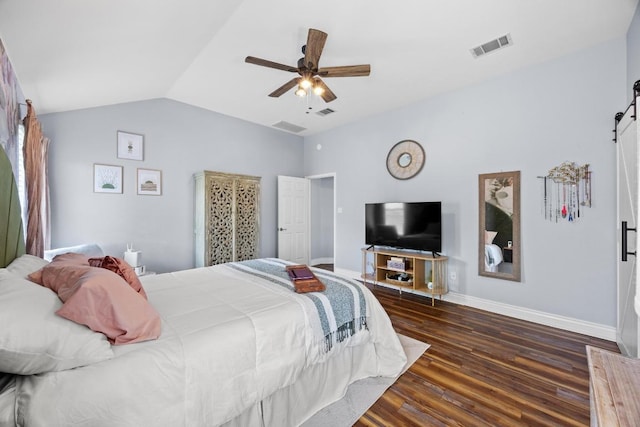 bedroom with visible vents, vaulted ceiling, a barn door, wood finished floors, and baseboards