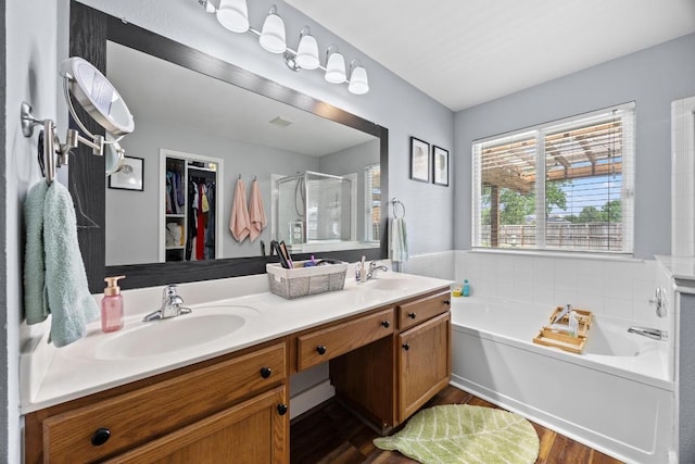 full bath with wood finished floors, a sink, a garden tub, and a stall shower