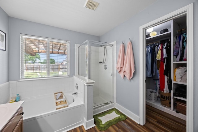 bathroom with visible vents, a stall shower, a bath, and wood finished floors