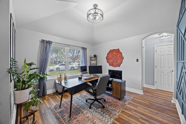 office space with a notable chandelier, arched walkways, dark wood finished floors, baseboards, and vaulted ceiling