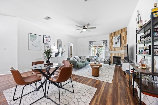 dining area featuring visible vents, wood finished floors, a fireplace, arched walkways, and a ceiling fan