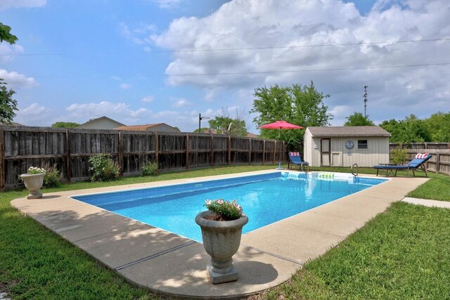 view of swimming pool with a fenced backyard, an outdoor structure, a yard, and a shed