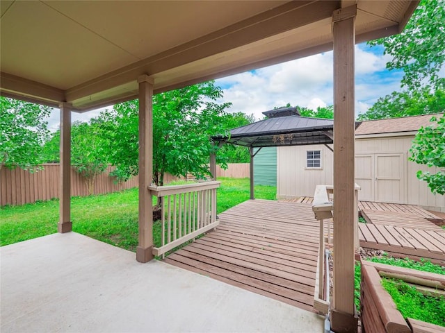 view of patio featuring a deck, an outbuilding, a gazebo, a fenced backyard, and a storage unit
