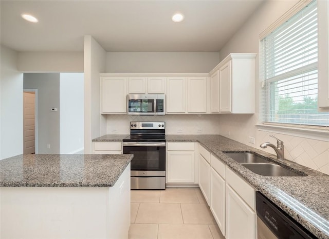 kitchen with white cabinets, appliances with stainless steel finishes, a sink, and tasteful backsplash