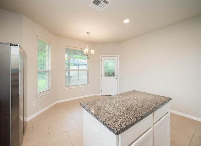 kitchen with white cabinets, a chandelier, freestanding refrigerator, stone counters, and visible vents