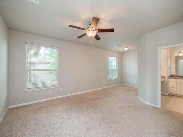 unfurnished bedroom featuring baseboards, ensuite bath, and light carpet