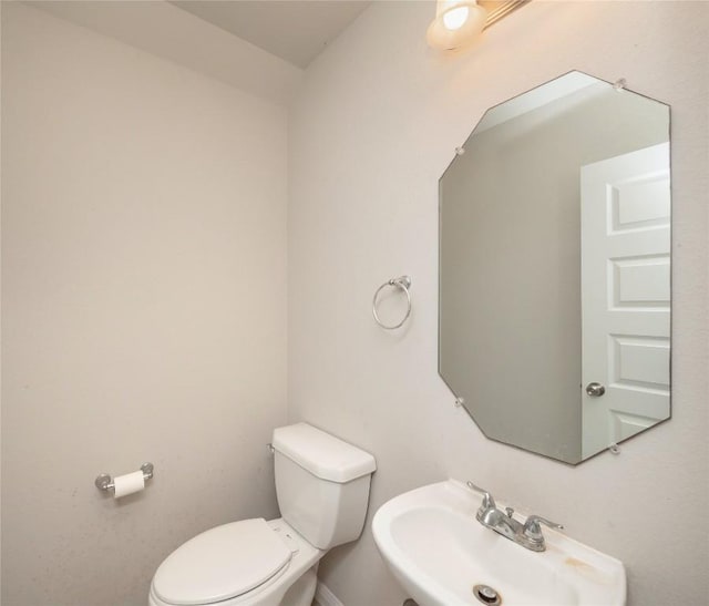 bathroom with baseboards, a sink, and toilet