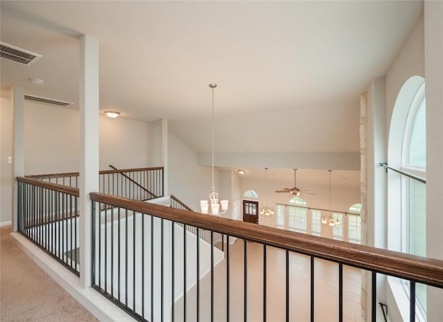 hallway featuring carpet flooring, visible vents, a notable chandelier, and an upstairs landing