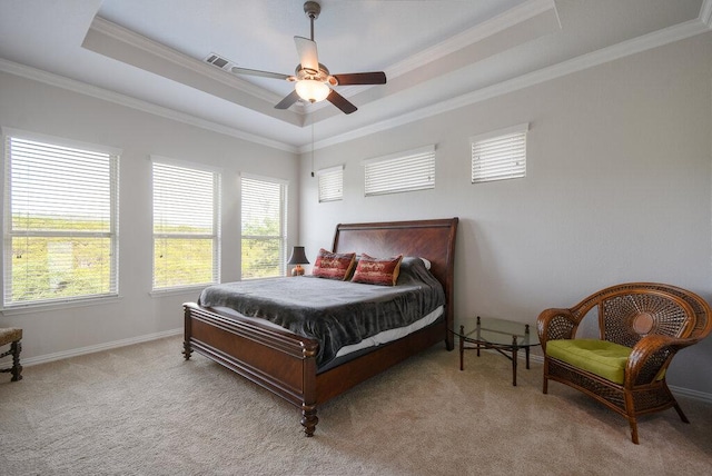 carpeted bedroom with multiple windows, ornamental molding, and a tray ceiling