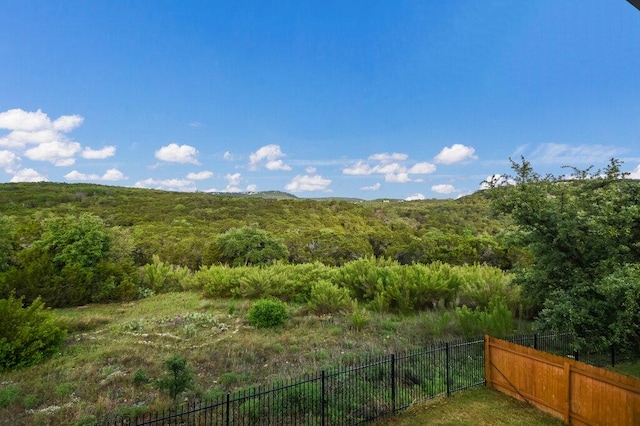 view of yard featuring fence and a wooded view