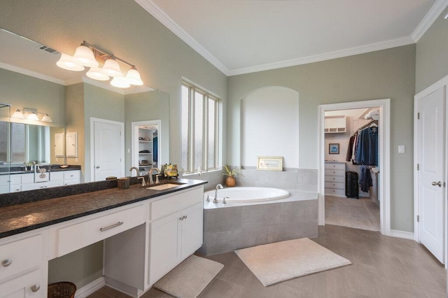 bathroom featuring vanity, ornamental molding, a garden tub, and a spacious closet