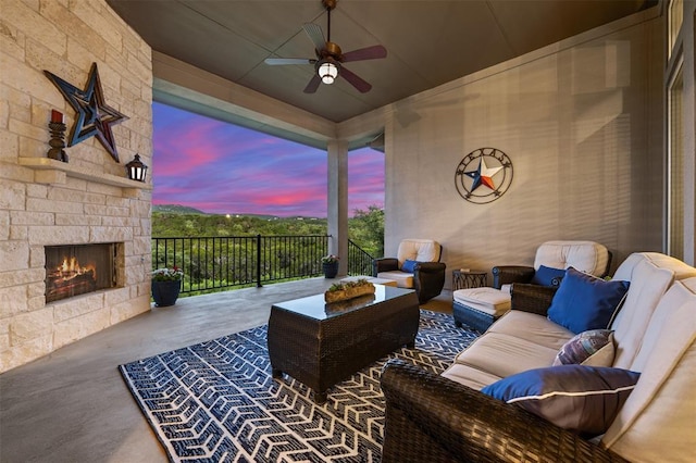 patio terrace at dusk featuring a ceiling fan and an outdoor living space with a fireplace