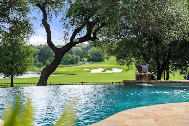 view of property's community with a lawn, a swimming pool, fence, and view of golf course